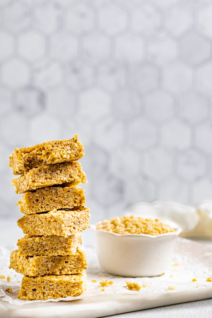 A stack of healthy rice krispie treats are on the left corner. A bowl of rice cereal is off to the side.