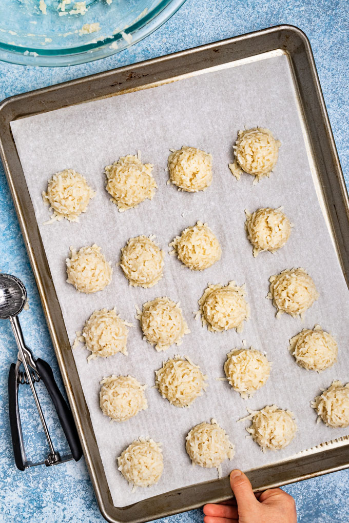 Coconut macaroon batter scooped out into cookies, on a baking sheet, before baking.