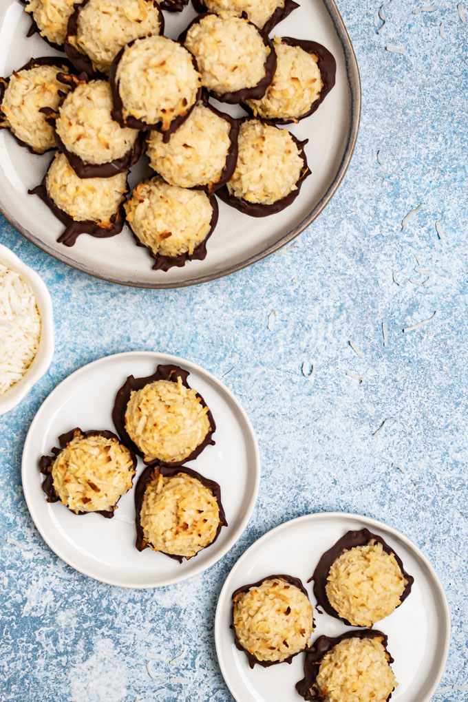Coconut macaroons on several plates on a light blue background. 