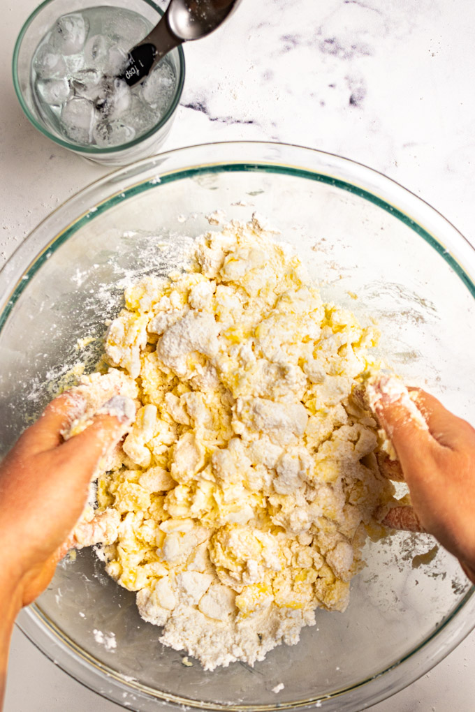 Hands mixing pie crust together in a bowl