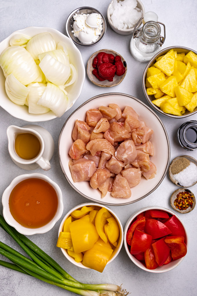Ingredients in bowls: chicken, bell peppers, onion, honey, pineapple, tomato paste etc.