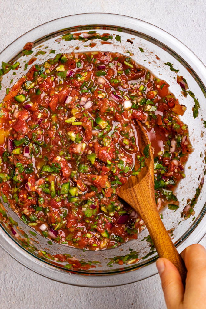 Easy homemade Salsa in a mixing bowl with a wooden spoon.