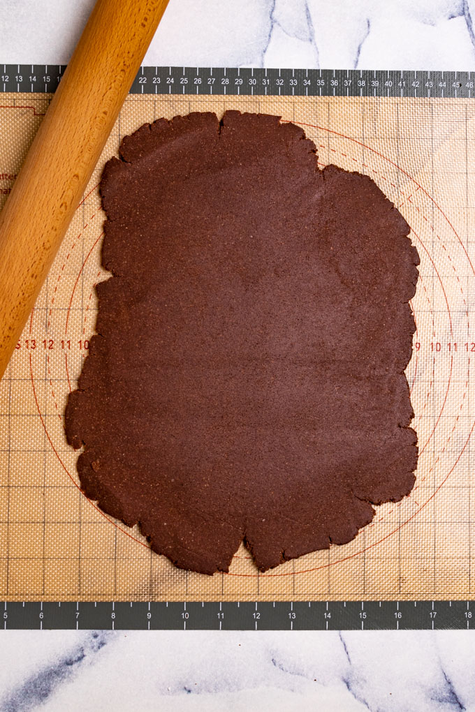 Thin mints cookie dough is rolled out on a baking mat.