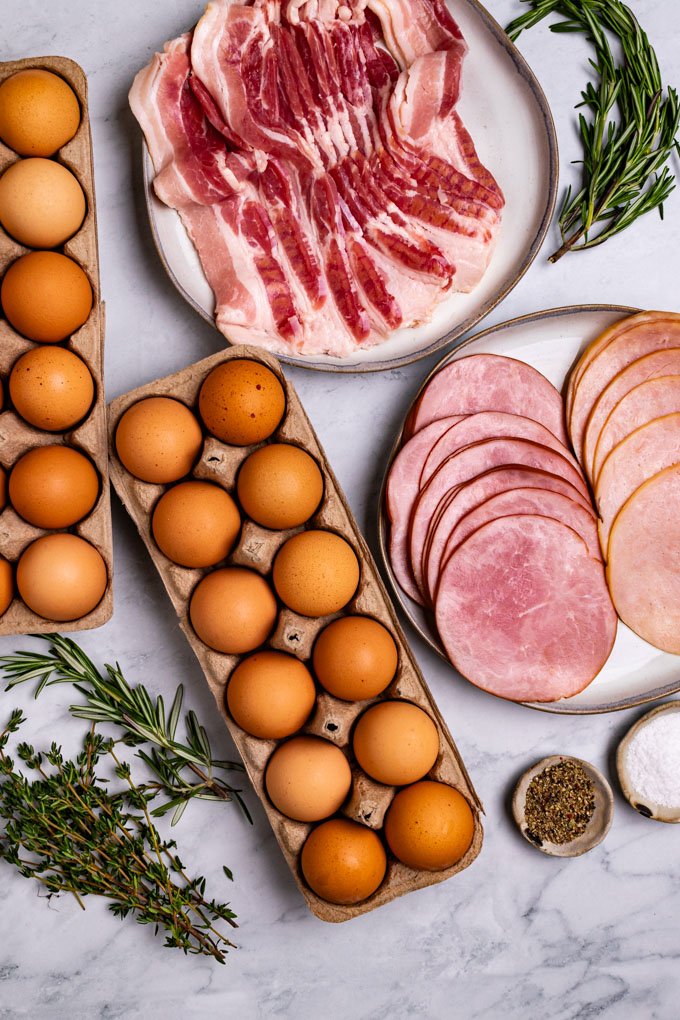 Overhead shot of ingredients for egg cups: eggs, ham, turkey, herbs, bacon, and salt and pepper!