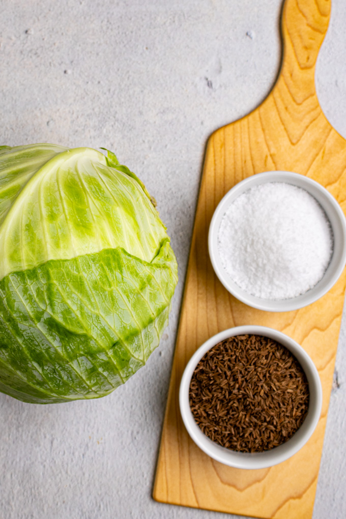 Ingredient shot for how to make sauerkraut: green cabbage, salt, and caraway seeds.