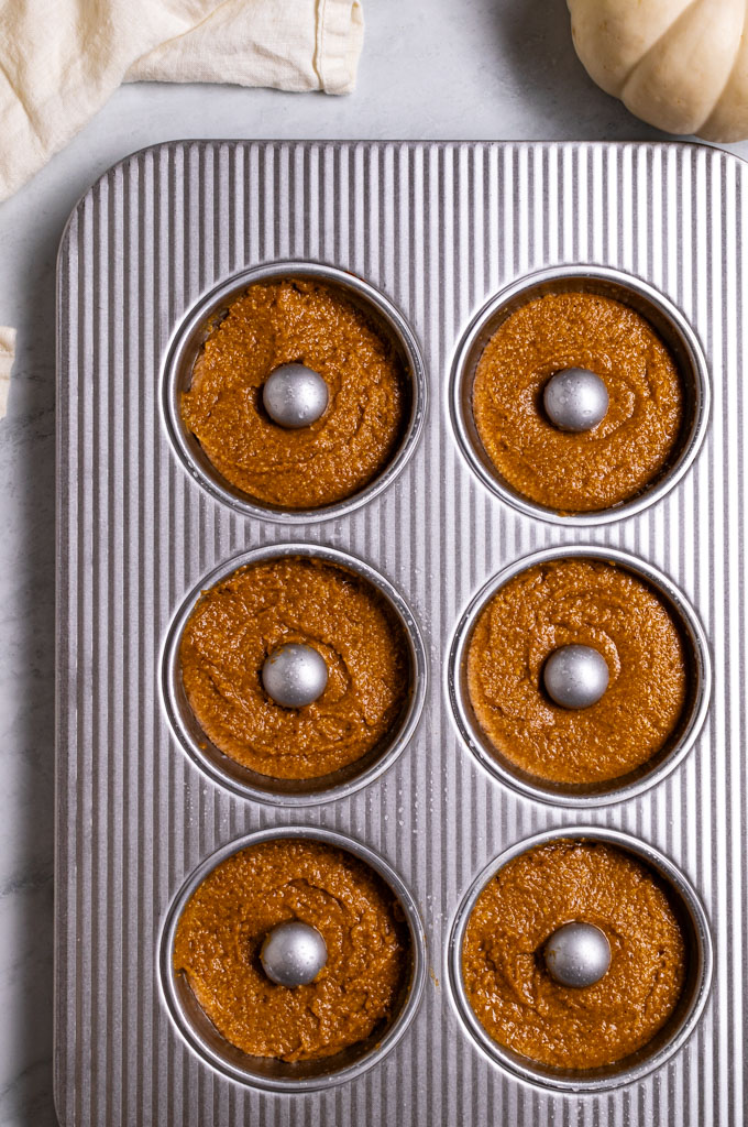 Overhead photo of unbaked donuts in a donut pan. 