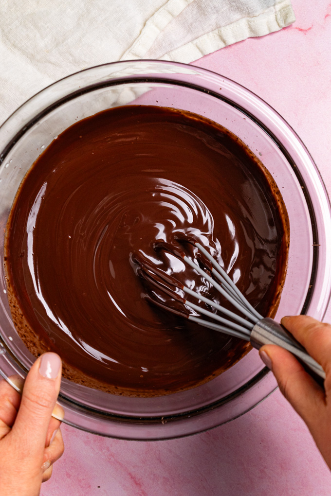 Overhead shot of chocolate ganache being whisked together in a small mixing bowl.